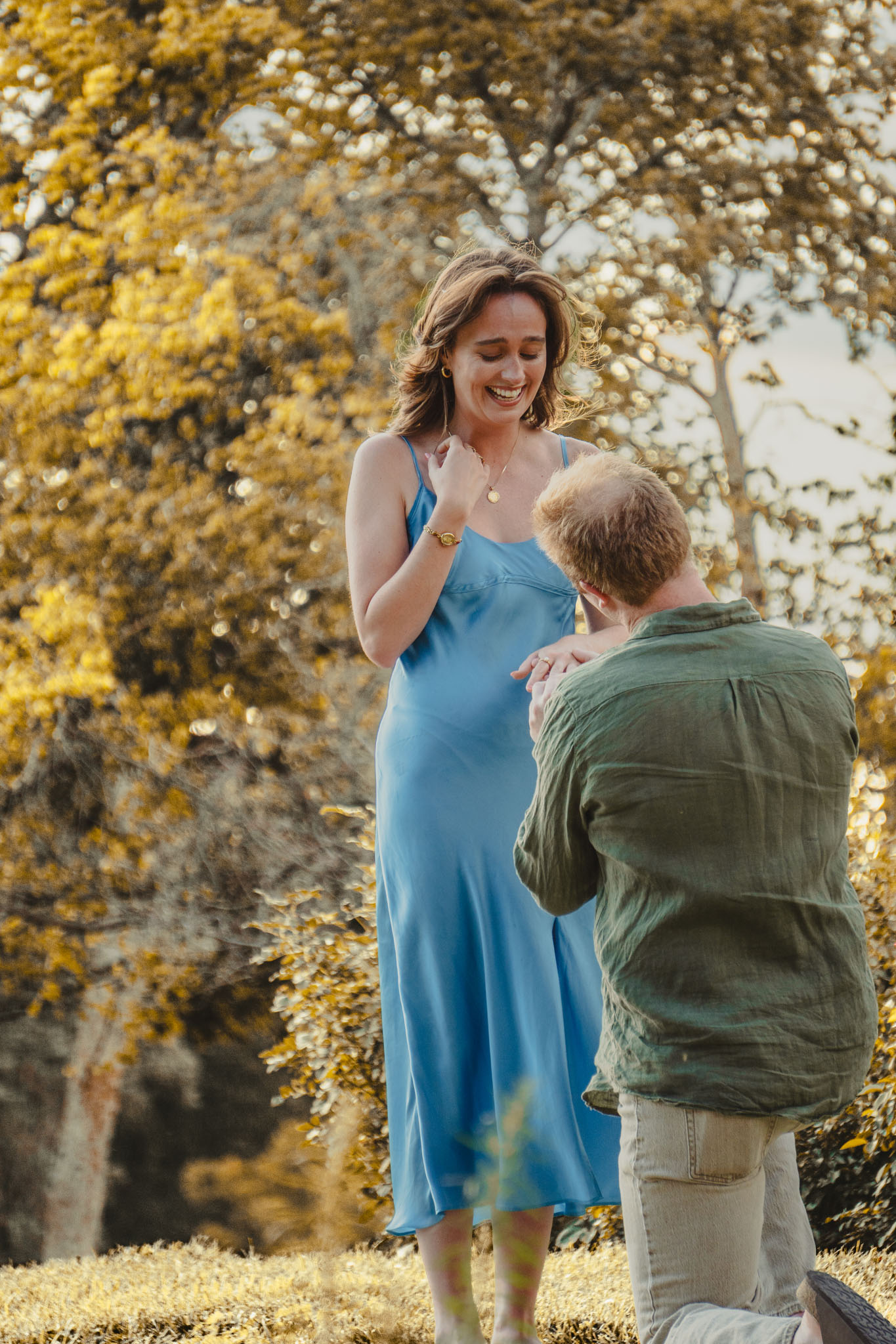 Smiling proposal reaction among golden autumn trees.