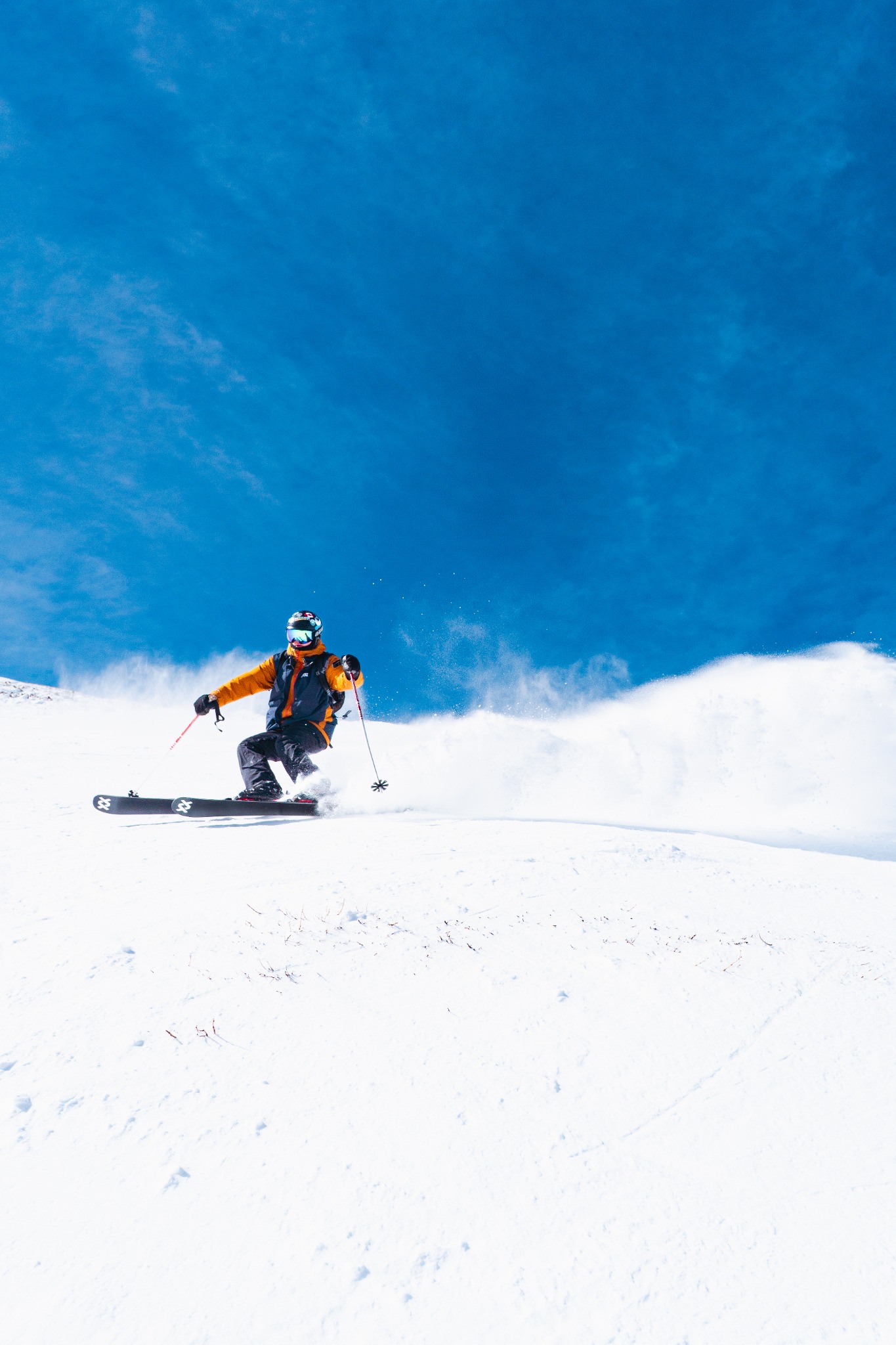 Skier cutting through powder on a snow-covered mountain slope.