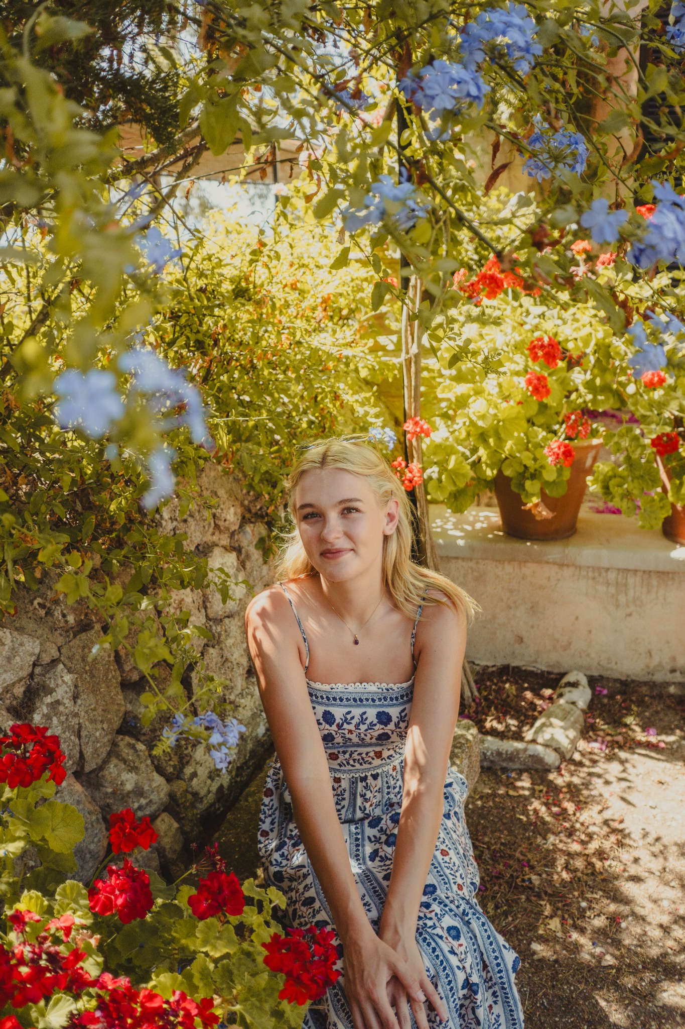 Relaxed seated portrait framed by flowers and greenery.